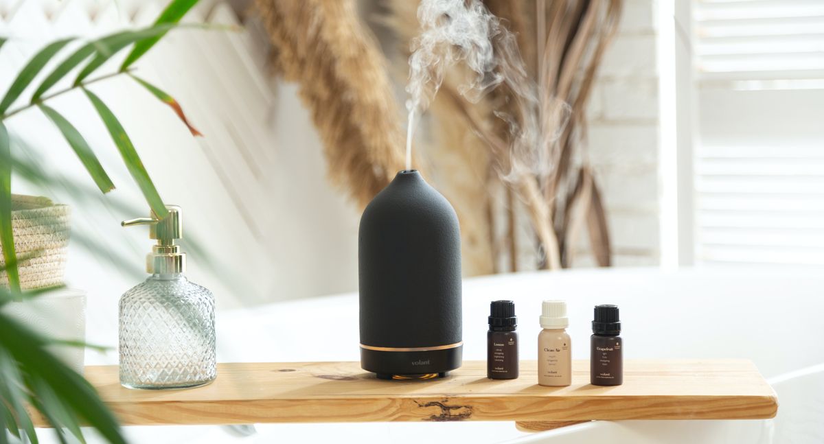 Different oils and a fragrance lamp on a bathtub shelf